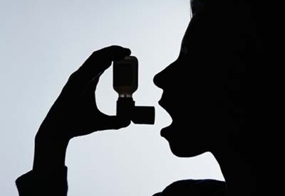 The silhouette of someone using an inhaler
